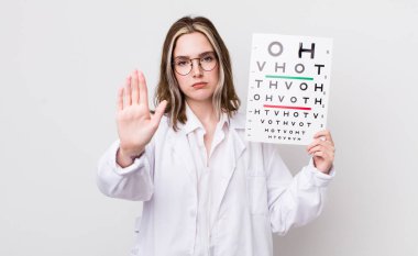 Beyaz kadın ciddi görünüyor. Avuç içinin açık olduğunu gösteriyor. Durdurma hareketi yapıyor. optik konsept