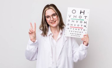 Güzel, beyaz bir kadın gülümsüyor ve arkadaş canlısı görünüyor. İki numarayı gösteriyor. optik konsept