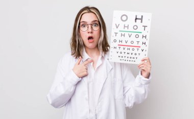 Ağzı açık, kendini işaret eden oldukça beyaz bir kadın şok olmuş ve şaşırmış görünüyor. optik konsept