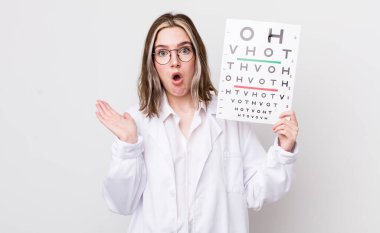 Kafkasyalı bir kadın şaşırmış ve şok olmuş görünüyor. Çenesi düşmüş ve elinde bir nesne var. optik konsept