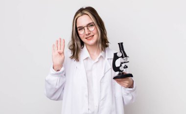 Güzel beyaz kadın gülümsüyor ve arkadaş canlısı görünüyor, dört numarayı gösteriyor. Mikroskop konseptine sahip bilim adamı