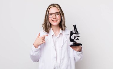 Oldukça beyaz bir kadın heyecanlı ve şaşırmış görünüyor. Mikroskop konseptine sahip bilim adamı