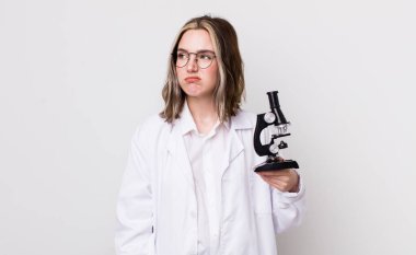 Kafkasyalı bir kadın üzgün, üzgün ya da kızgın ve yana bakıyor. Mikroskop konseptine sahip bilim adamı