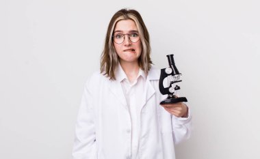 Kafası karışmış ve kafası karışmış beyaz bir kadın. Mikroskop konseptine sahip bilim adamı