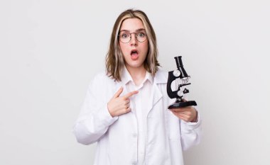 Ağzı açık, kendini işaret eden oldukça beyaz bir kadın şok olmuş ve şaşırmış görünüyor. Mikroskop konseptine sahip bilim adamı