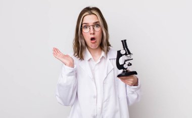 Kafkasyalı bir kadın şaşırmış ve şok olmuş görünüyor. Çenesi düşmüş ve elinde bir nesne var. Mikroskop konseptine sahip bilim adamı
