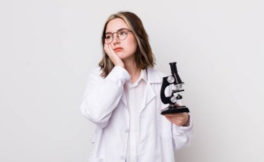 Oldukça beyaz bir kadın bıkkın, hayal kırıklığına uğramış ve yorucu bir geceden sonra uykulu hissediyor. Mikroskop konseptine sahip bilim adamı