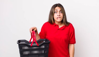 Şaşkın ve şaşkın görünen güzel İspanyol kadın. boş alışveriş sepeti kavramı