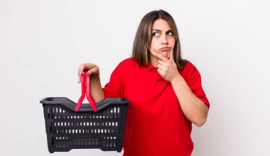 Düşünen, kuşkucu ve kafası karışık bir İspanyol kadın. boş alışveriş sepeti kavramı