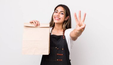 Güzel İspanyol kadın gülümsüyor ve arkadaş canlısı görünüyor, üç numarayı gösteriyor. teslimat ve paket konsepti