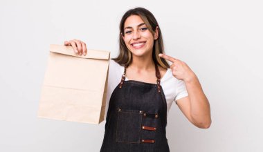 Güzel, İspanyol bir kadın, kendine güvenerek kendi gülüşünü işaret ediyor. teslimat ve paket konsepti