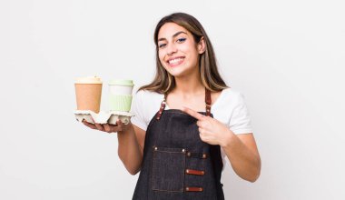 Güzel İspanyol kadın neşeyle gülümsüyor, mutlu hissediyor ve bir tarafı işaret ediyor. kahve konseptini kaldır.