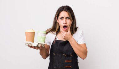 Ağzı ve gözleri sonuna kadar açık ve eli çenesinde olan güzel İspanyol bir kadın. kahve konseptini kaldır.