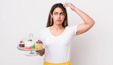 Güzel İspanyol kadın mutlu bir şekilde gülümsüyor ve hayal kuruyor ya da şüphe ediyor. Ev yapımı kek konsepti