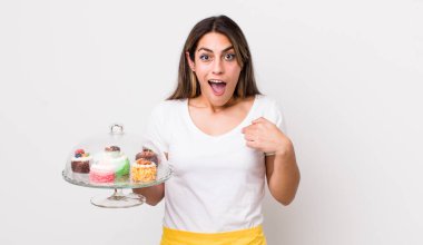 Güzel İspanyol bir kadın mutlu hissediyor ve heyecanla kendini işaret ediyor. Ev yapımı kek konsepti