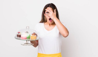 Güzel İspanyol kadın şok olmuş, korkmuş ya da korkmuş görünüyor. Yüzü elle kapatılmış. Ev yapımı kek konsepti