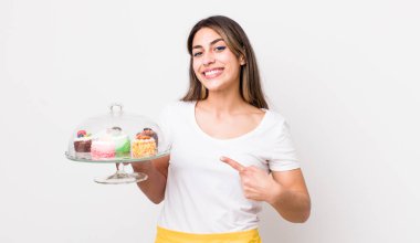 Güzel İspanyol kadın neşeyle gülümsüyor, mutlu hissediyor ve bir tarafı işaret ediyor. Ev yapımı kek konsepti