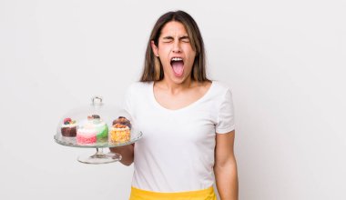 Oldukça İspanyol bir kadın agresif bir şekilde bağırıyor, çok kızgın görünüyor. Ev yapımı kek konsepti