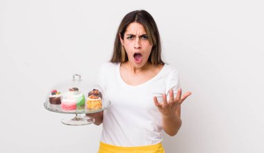 Güzel, İspanyol bir kadın sinirli, sinirli ve sinirli görünüyor. Ev yapımı kek konsepti