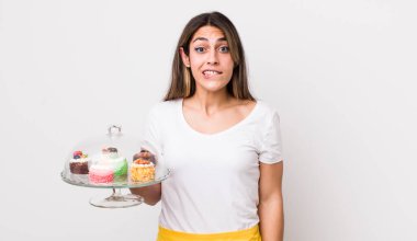 Şaşkın ve şaşkın görünen güzel İspanyol kadın. Ev yapımı kek konsepti