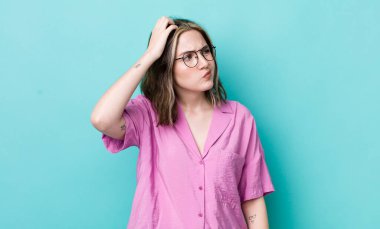 Kafası karışmış, kafası karışmış, kaşınan ve yan tarafa bakan beyaz bir kadın.