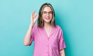 Güzel, beyaz bir kadın mutlu, rahat ve tatmin olmuş hissediyor. Onayını iyi bir hareketle gösteriyor. Gülümsüyor.