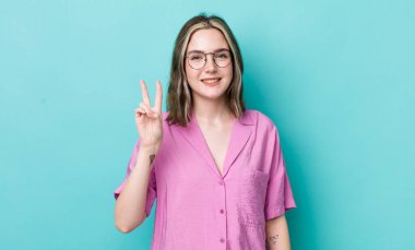 pretty caucasian woman smiling and looking friendly, showing number two or second with hand forward, counting down