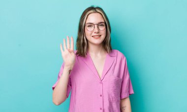 pretty caucasian woman smiling and looking friendly, showing number four or fourth with hand forward, counting down
