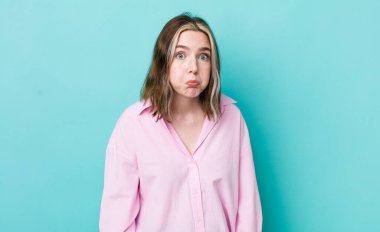 pretty caucasian woman with a goofy, crazy, surprised expression, puffing cheeks, feeling stuffed, fat and full of food