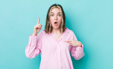 pretty caucasian woman feeling proud and surprised, pointing to self confidently, feeling like successful number one