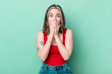 pretty caucasian woman feeling worried, upset and scared, covering mouth with hands, looking anxious and having messed up