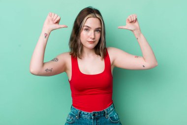 pretty caucasian woman feeling proud, arrogant and confident, looking satisfied and successful, pointing to self