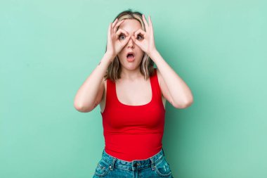 pretty caucasian woman feeling shocked, amazed and surprised, holding glasses with astonished, disbelieving look