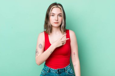pretty caucasian woman feeling happy, positive and successful, with hand making v shape over chest, showing victory or peace