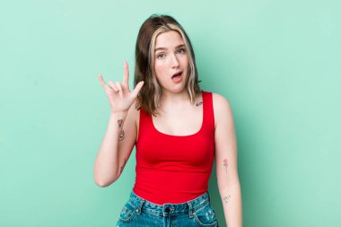 pretty caucasian woman feeling happy, fun, confident, positive and rebellious, making rock or heavy metal sign with hand