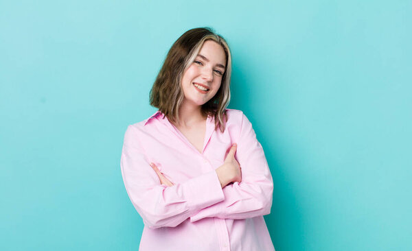 pretty caucasian woman laughing happily with arms crossed, with a relaxed, positive and satisfied pose