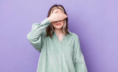 pretty caucasian woman covering eyes with one hand feeling scared or anxious, wondering or blindly waiting for a surprise