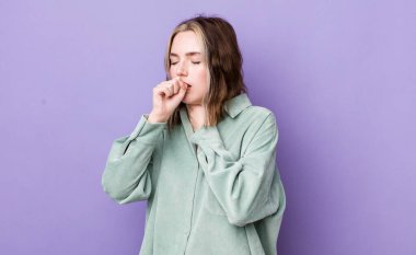 pretty caucasian woman feeling ill with a sore throat and flu symptoms, coughing with mouth covered