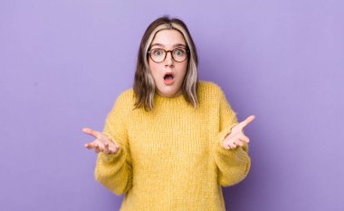 pretty caucasian woman open-mouthed and amazed, shocked and astonished with an unbelievable surprise