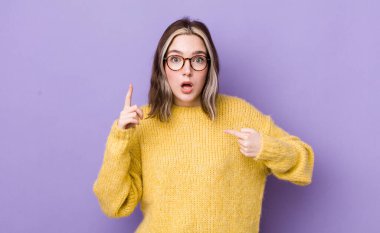 pretty caucasian woman feeling proud and surprised, pointing to self confidently, feeling like successful number one