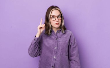 pretty caucasian woman feeling like a genius holding finger proudly up in the air after realizing a great idea, saying eureka