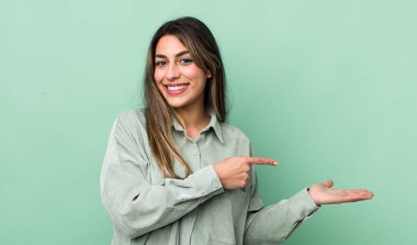 Güzel İspanyol kadın gülümsüyor, mutlu, kaygısız ve tatmin olmuş hissediyor, fotokopi alanındaki konsepte ya da fikre işaret ediyor.