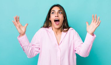 Güzel İspanyol kadın kendini mutlu, şaşkın, şanslı ve şaşırmış hissediyor. Zaferi kutlarken iki eli havada.