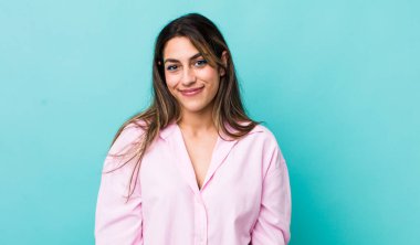 Güzel İspanyol bir kadın pozitif ve kendinden emin gülümsüyor. Tatmin olmuş, arkadaş canlısı ve mutlu görünüyor.