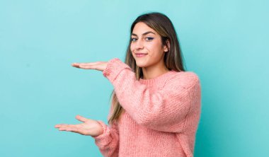 Güzel İspanyol bir kadın iki eli yanda bir objeyi tutuyor fotokopi alanında, bir objeyi gösteriyor, sunuyor ya da reklamını yapıyor.