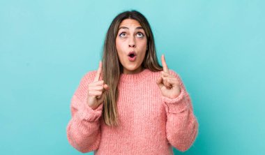 Güzel İspanyol bir kadın şaşkınlık içinde ve ağzı açık. Şok olmuş ve şaşırmış bir bakışla yukarı bakıyor.