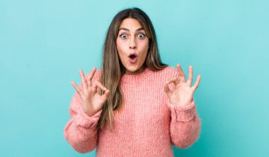 Güzel İspanyol kadın şok olmuş, şaşırmış ve şaşırmış hissediyor. Onaylıyor. İki eliyle işaret veriyor.