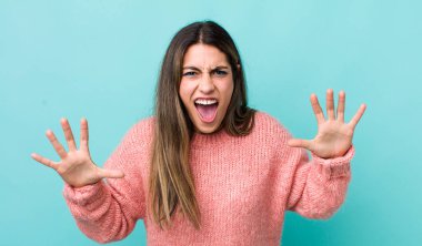 Güzel İspanyol kadın panik ya da öfke içinde bağırıyor, şok olmuş, korkmuş ya da öfkeli, elleri başının yanında.