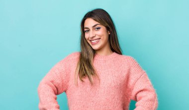 Güzel, İspanyol bir kadın neşeli, neşeli, mutlu, kendinden emin ve rahat bir ifadeyle gülümsüyor.