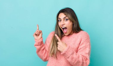 Güzel İspanyol bir kadın kendini neşeli ve şaşırmış hissediyor. Şok olmuş bir ifadeyle gülümsüyor ve bir tarafı işaret ediyor.